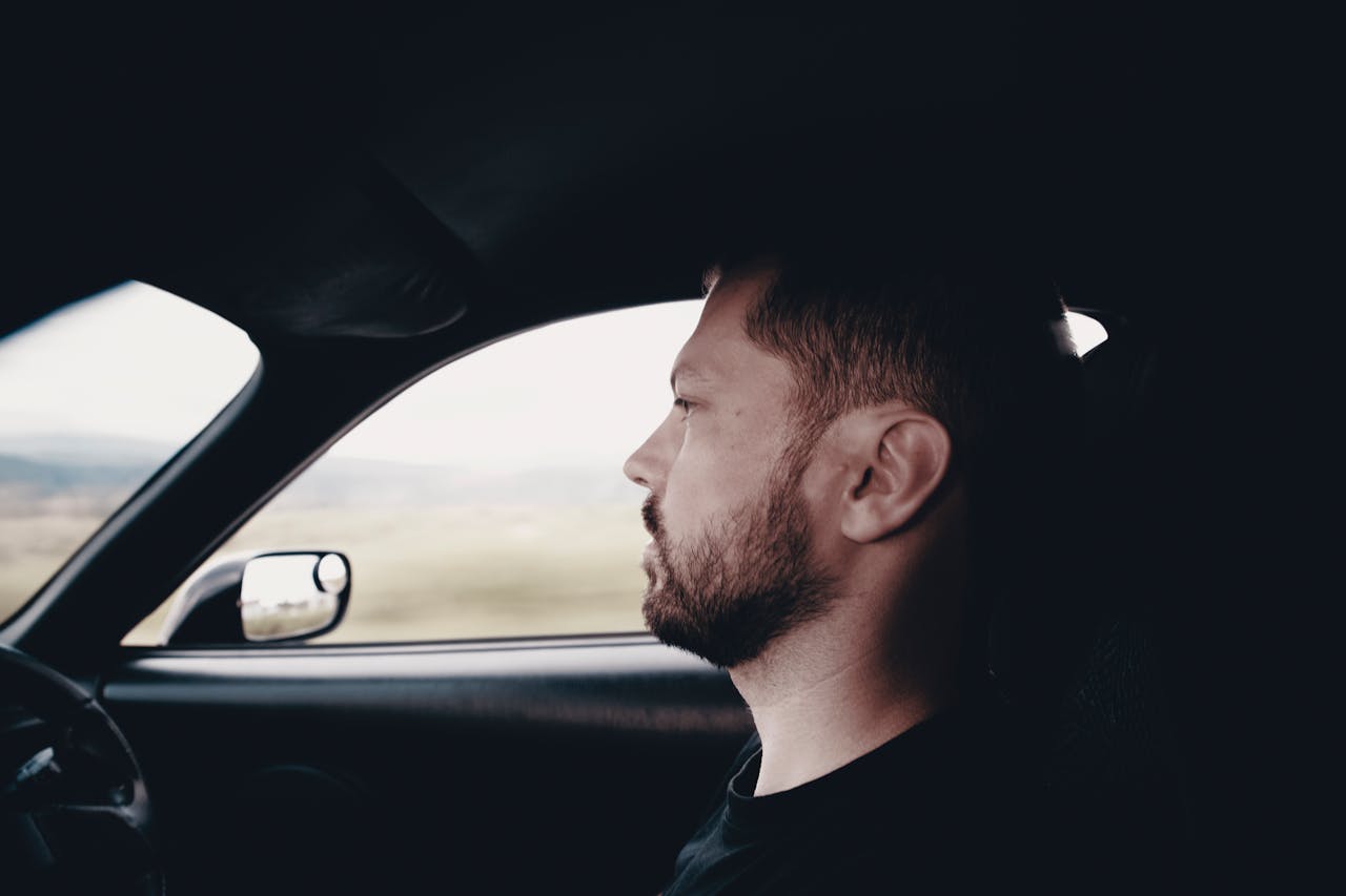 Home Side profile of a bearded man driving a car, focused and intent on the road.